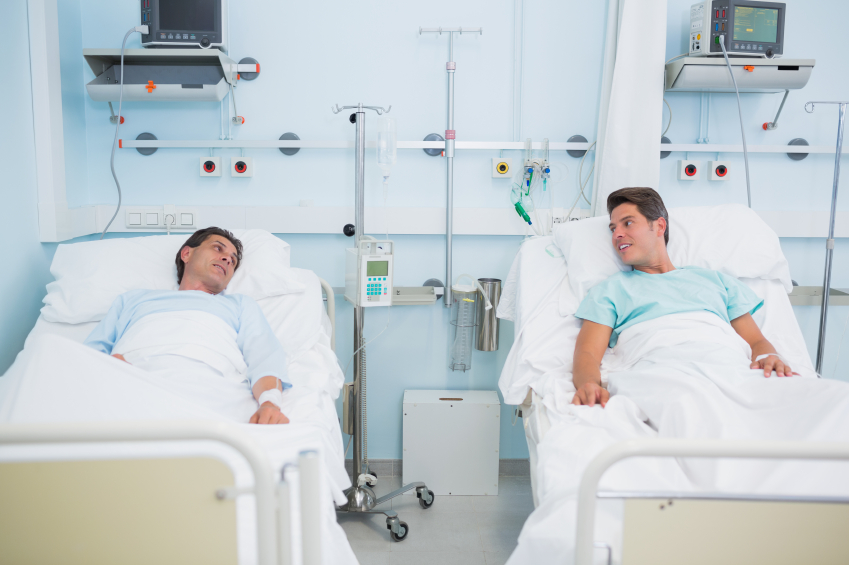 Patients talking together while lying in beds in a hospital ward